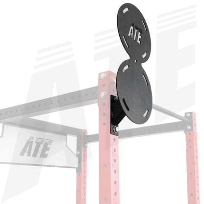 Black dual-hole weight plate mounting brackets attached to a pink power rack, with the ATE logo visible on the brackets and faintly in the background.